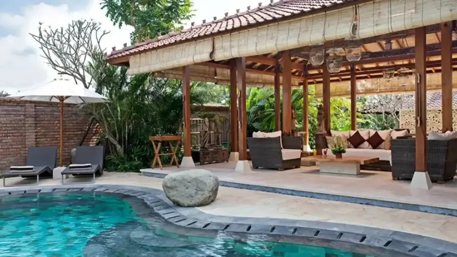 Open timber pavilion beside a pool in Bali